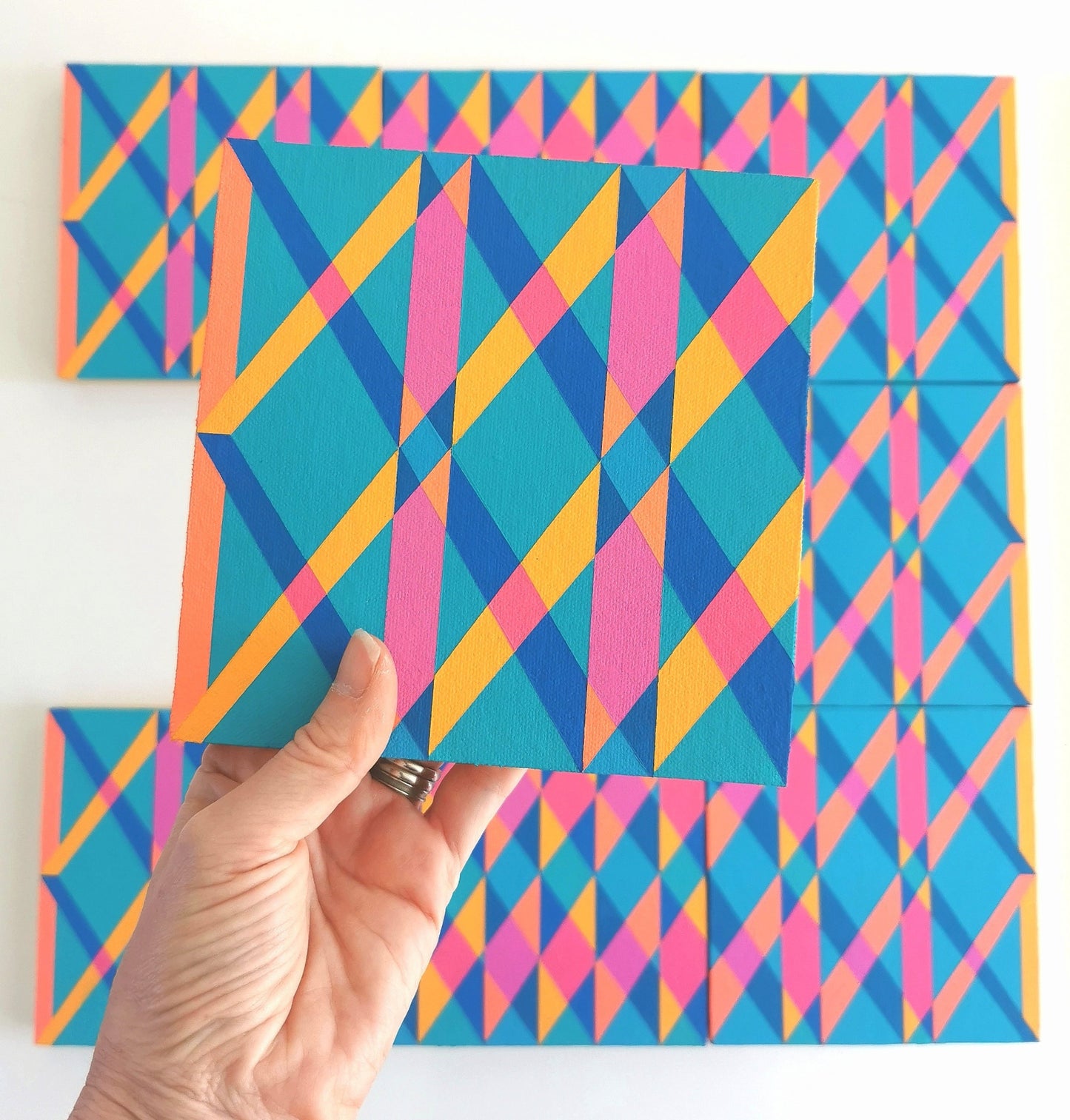 “O PG7/PB15:3 – PB15:3/PG7”– one module from Victoria Mardon’s B.E.L.O.N.G.I.N.G series held in front of the full artwork. Colourful geometric pattern on canvas, shown in context.