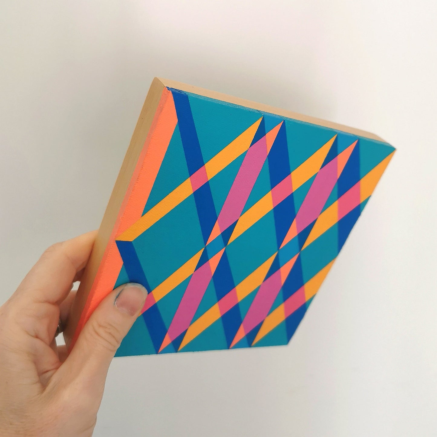 Hand holding “O PG7/PB15:3 – PB15:3/PG7” – a small 15 x 15 cm canvas with a colourful geometric pattern. Part of Victoria Mardon’s B.E.L.O.N.G.I.N.G series, shown for scale.
