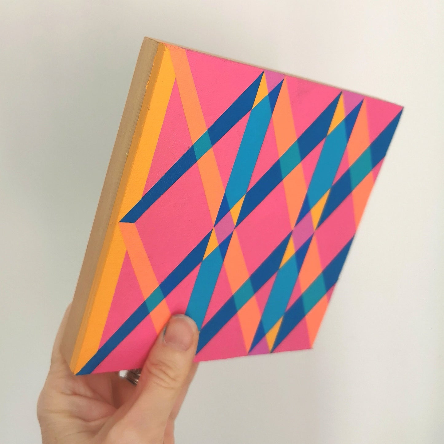 Hand holding “O PV19 PR122” – a small 15 x 15 cm canvas with a colourful geometric pattern. Part of Victoria Mardon’s B.E.L.O.N.G.I.N.G series, shown for scale.