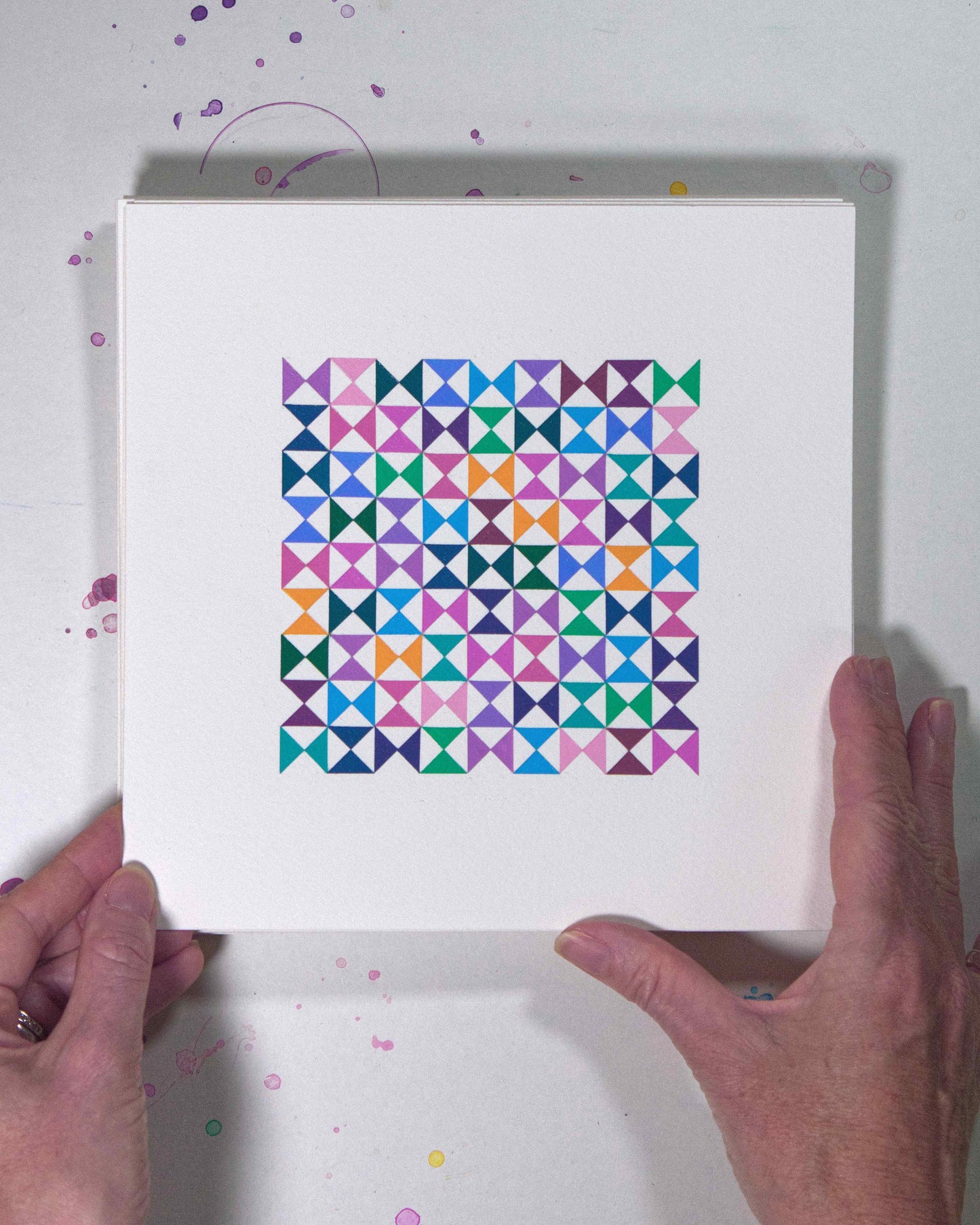 Hands holding a bold, graphic multicoloured abstract painting with repeating geometric shapes, 7 July – 007/365 (46210/365) by Victoria Mardon, 365: A Year in Colour series.