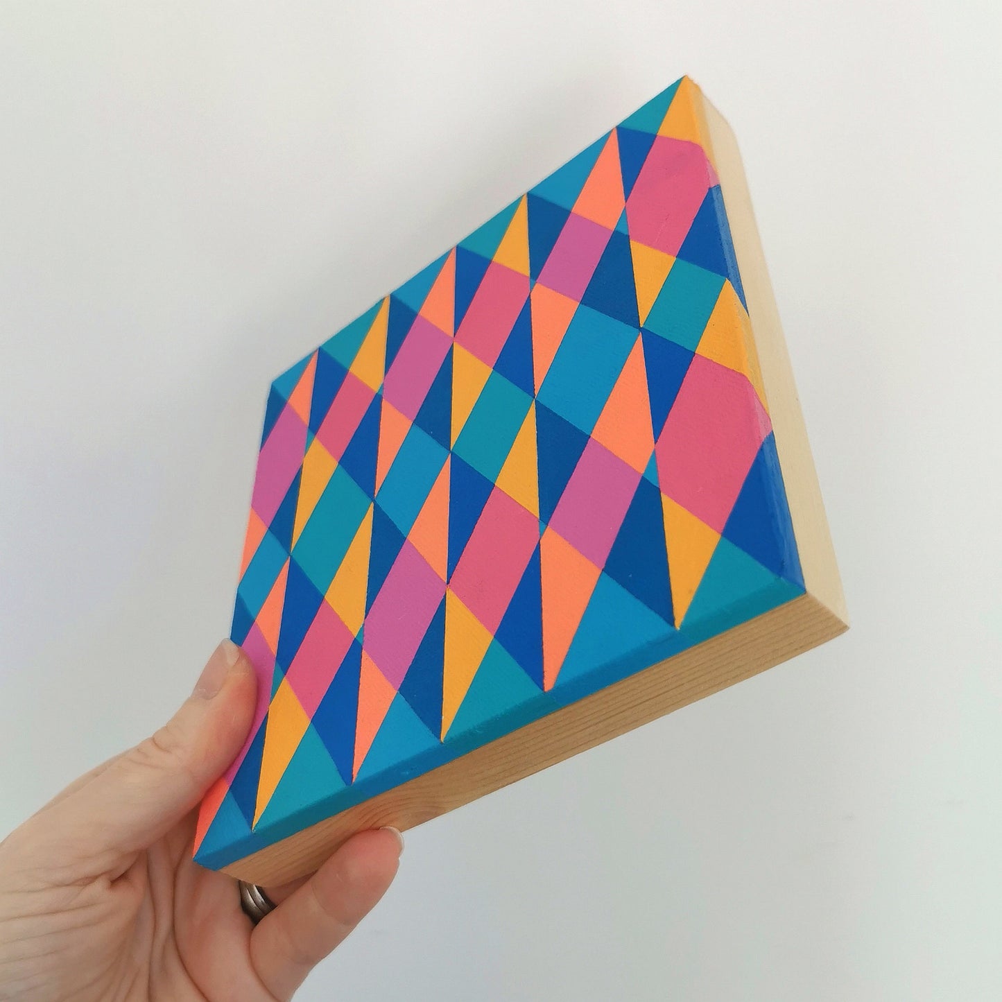 Hand holding “E PG7/PB15:3 – PB15:3/PG7” – a small 15 x 15 cm canvas with a colourful geometric pattern. Part of Victoria Mardon’s B.E.L.O.N.G.I.N.G series, shown for scale.
