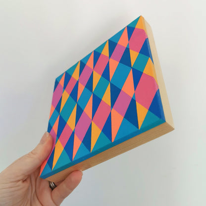 Hand holding “E PG7/PB15:3 – PB15:3/PG7” – a small 15 x 15 cm canvas with a colourful geometric pattern. Part of Victoria Mardon’s B.E.L.O.N.G.I.N.G series, shown for scale.