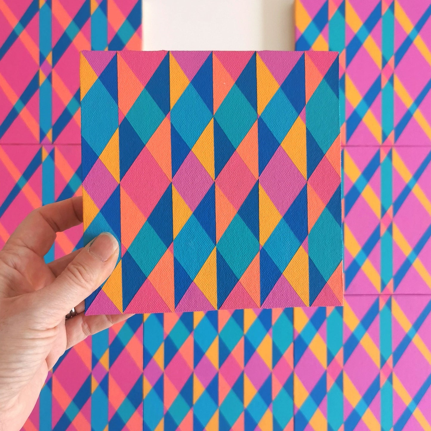 “E PV19 PR122” – one module from Victoria Mardon’s B.E.L.O.N.G.I.N.G series held in front of the full artwork. Colourful geometric pattern on canvas, shown in context.