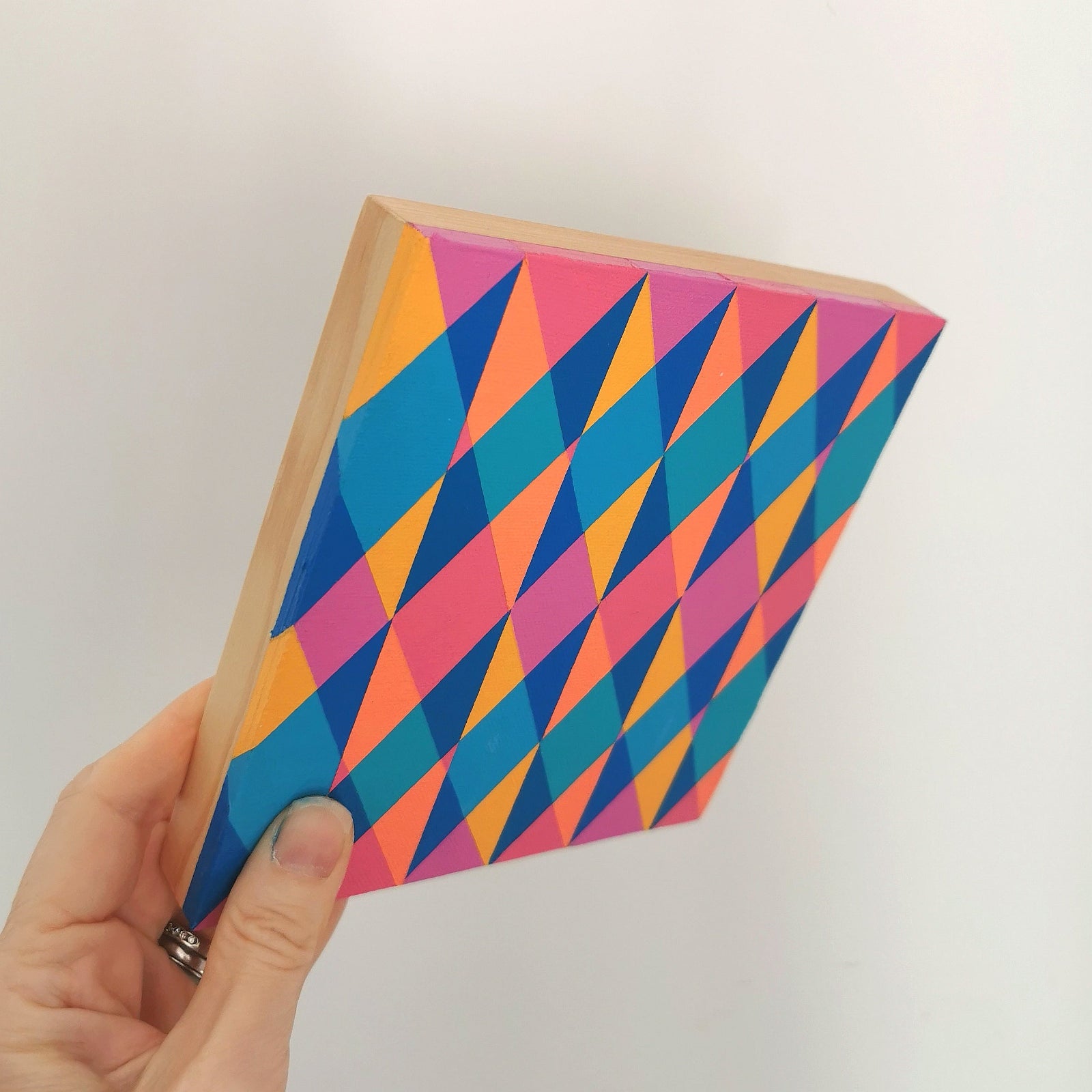 Hand holding “E PV19 PR122” – a small 15 x 15 cm canvas with a colourful geometric pattern. Part of Victoria Mardon’s B.E.L.O.N.G.I.N.G series, shown for scale.