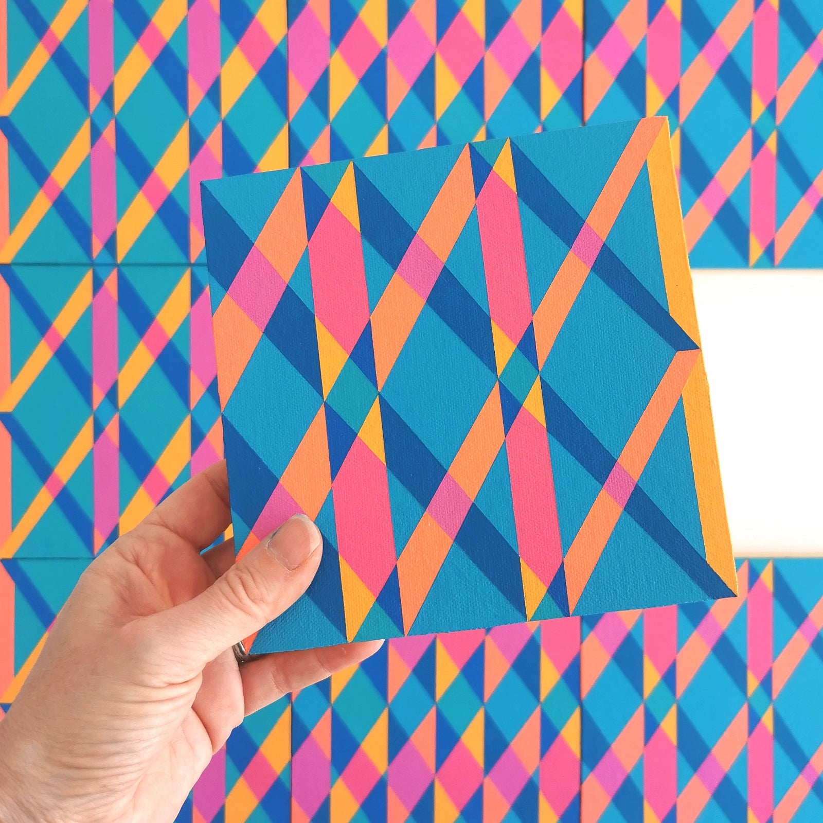 “G1 PG7/PB15:3 – PB15:3/PG7” – one module from Victoria Mardon’s B.E.L.O.N.G.I.N.G series held in front of the full artwork. Colourful geometric pattern on canvas, shown in context.