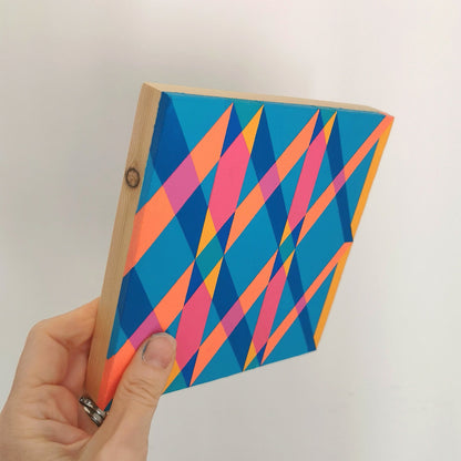 Hand holding “G2 PG7/PB15:3 – PB15:3/PG7” – a small 15 x 15 cm canvas with a colourful geometric pattern. Part of Victoria Mardon’s B.E.L.O.N.G.I.N.G series, shown for scale.