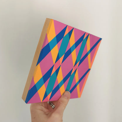 Hand holding “G2 PV19 PR122” – a small 15 x 15 cm canvas with a colourful geometric pattern. Part of Victoria Mardon’s B.E.L.O.N.G.I.N.G series, shown for scale.