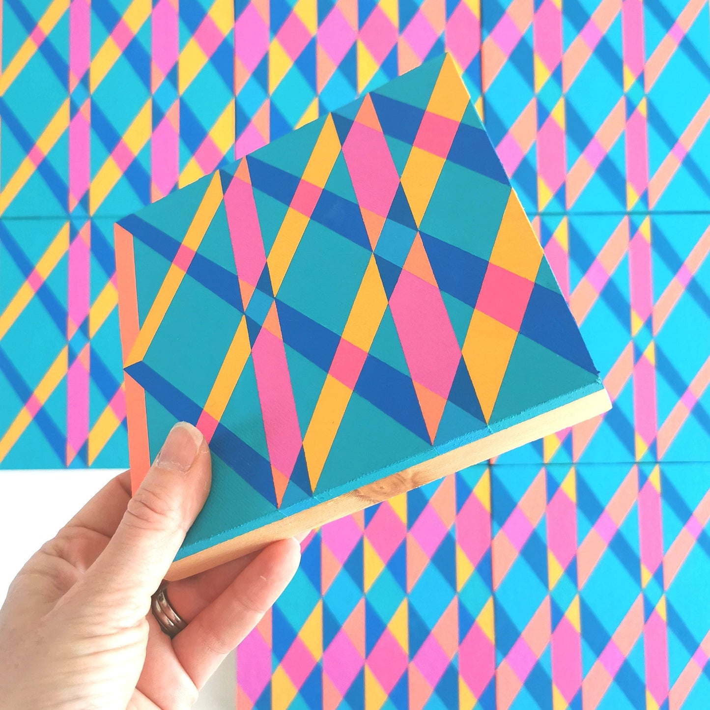 “I PG7/PB15:3 – PB15:3/PG7” – one module from Victoria Mardon’s B.E.L.O.N.G.I.N.G series held in front of the full artwork. Colourful geometric pattern on canvas, shown in context.