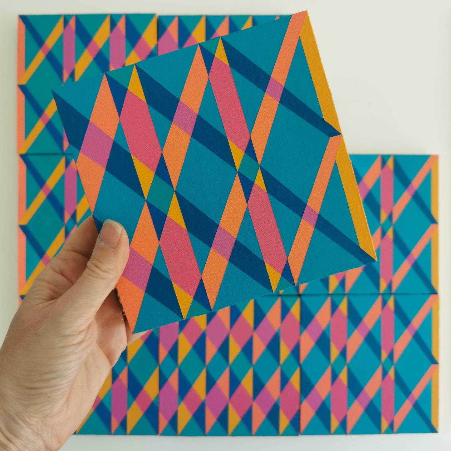 “L PG7/PB15:3 – PB15:3/PG7” – one module from Victoria Mardon’s B.E.L.O.N.G.I.N.G series held in front of the full artwork. Colourful geometric pattern on canvas, shown in context.