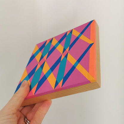 Hand holding “L PV19 PR122” – a small 15 x 15 cm canvas with a colourful geometric pattern. Part of Victoria Mardon’s B.E.L.O.N.G.I.N.G series, shown for scale.