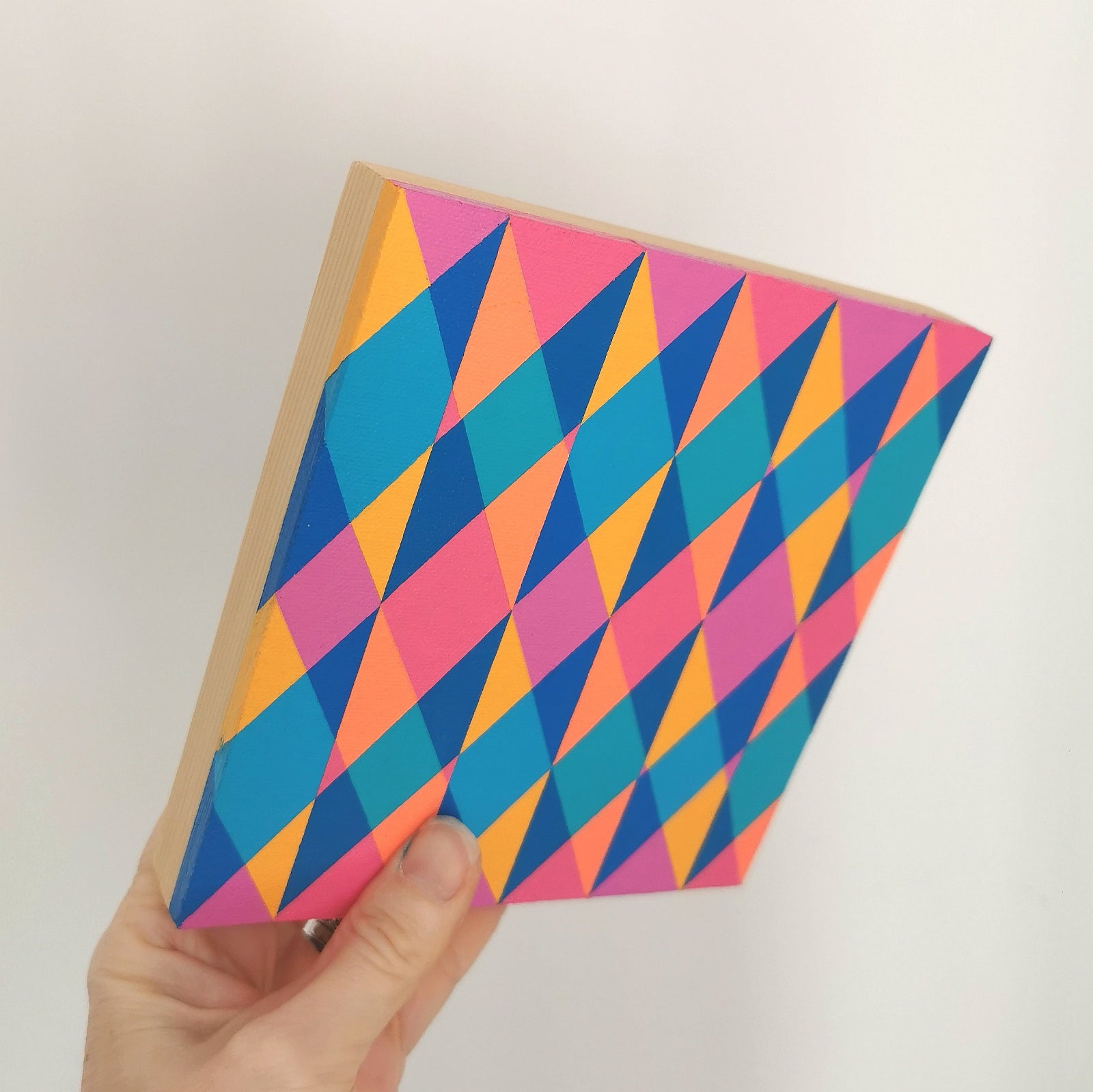 Hand holding “N1 PV19 PR122” – a small 15 x 15 cm canvas with a colourful geometric pattern. Part of Victoria Mardon’s B.E.L.O.N.G.I.N.G series, shown for scale.