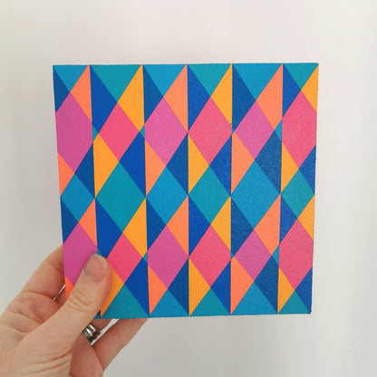 Hand holding “N2 PG7/PB15:3 – PB15:3/PG7” – a small 15 x 15 cm canvas with a colourful geometric pattern. Part of Victoria Mardon’s B.E.L.O.N.G.I.N.G series, shown for scale.