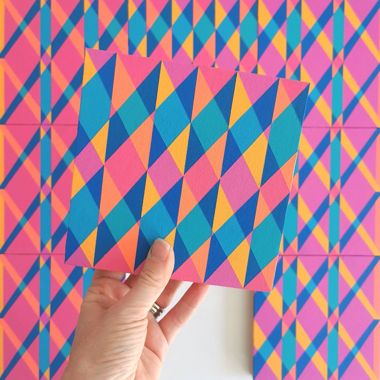 “N2 PV19 PR122” – one module from Victoria Mardon’s B.E.L.O.N.G.I.N.G series held in front of the full artwork. Colourful geometric pattern on canvas, shown in context.