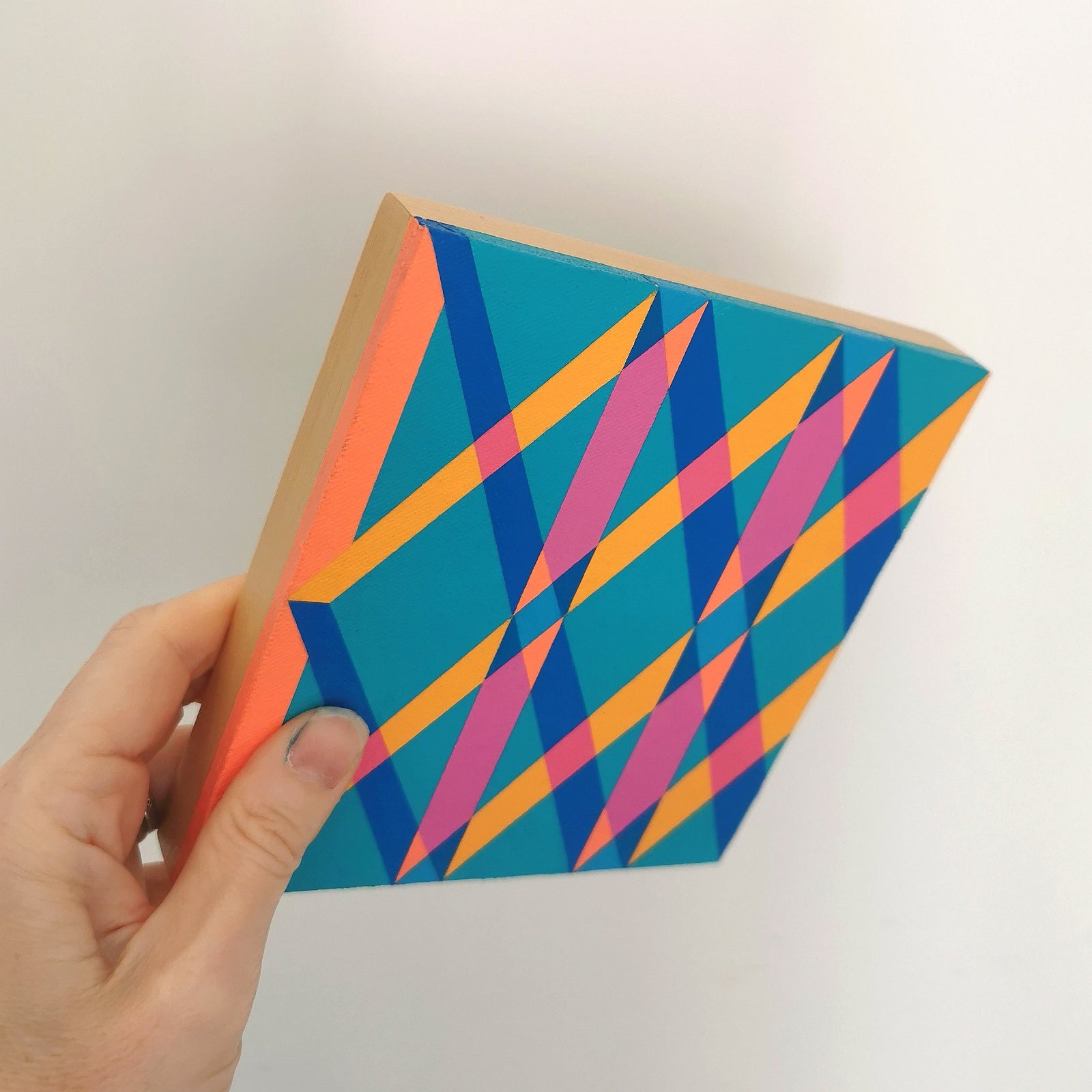 Hand holding “O PG7/PB15:3 – PB15:3/PG7” – a small 15 x 15 cm canvas with a colourful geometric pattern. Part of Victoria Mardon’s B.E.L.O.N.G.I.N.G series, shown for scale.