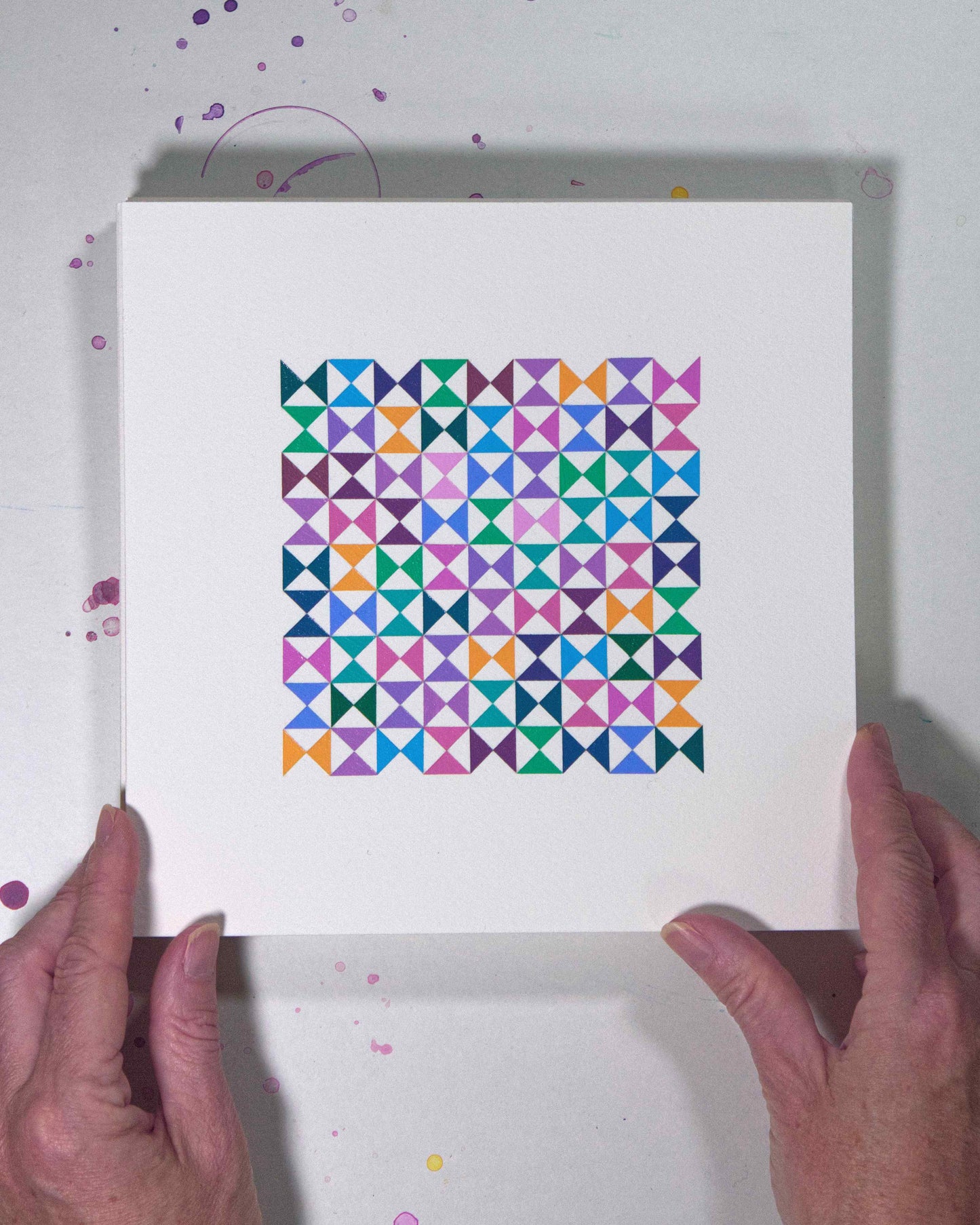 Hands holding a bold, graphic multicoloured abstract painting with repeating geometric shapes, 2 August – 033/365 (46236/365) by Victoria Mardon, 365: A Year in Colour series.