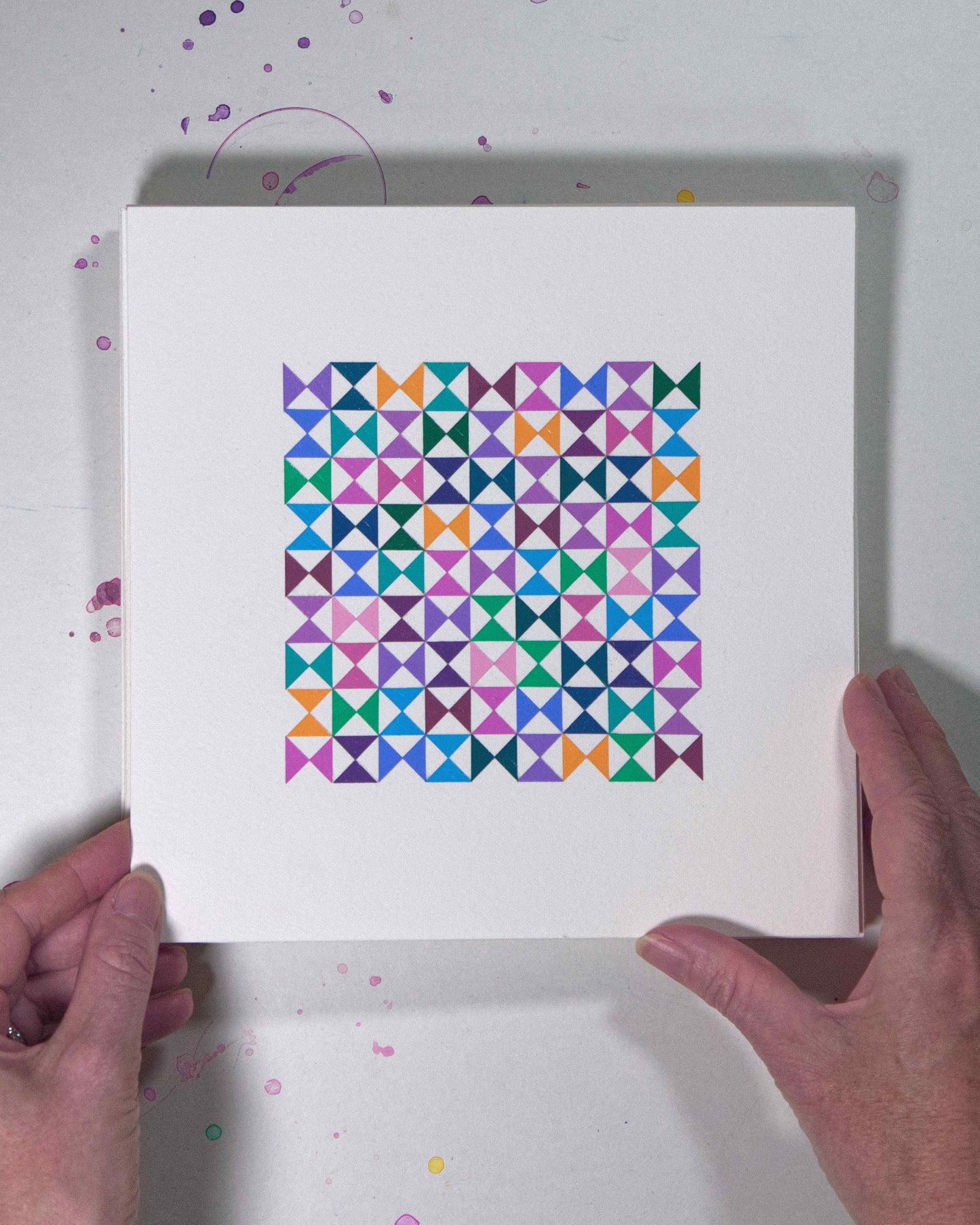 Hands holding a bold, graphic multicoloured abstract painting with repeating geometric shapes, 2 July – 002/365 (46205/365) by Victoria Mardon, 365: A Year in Colour series.
