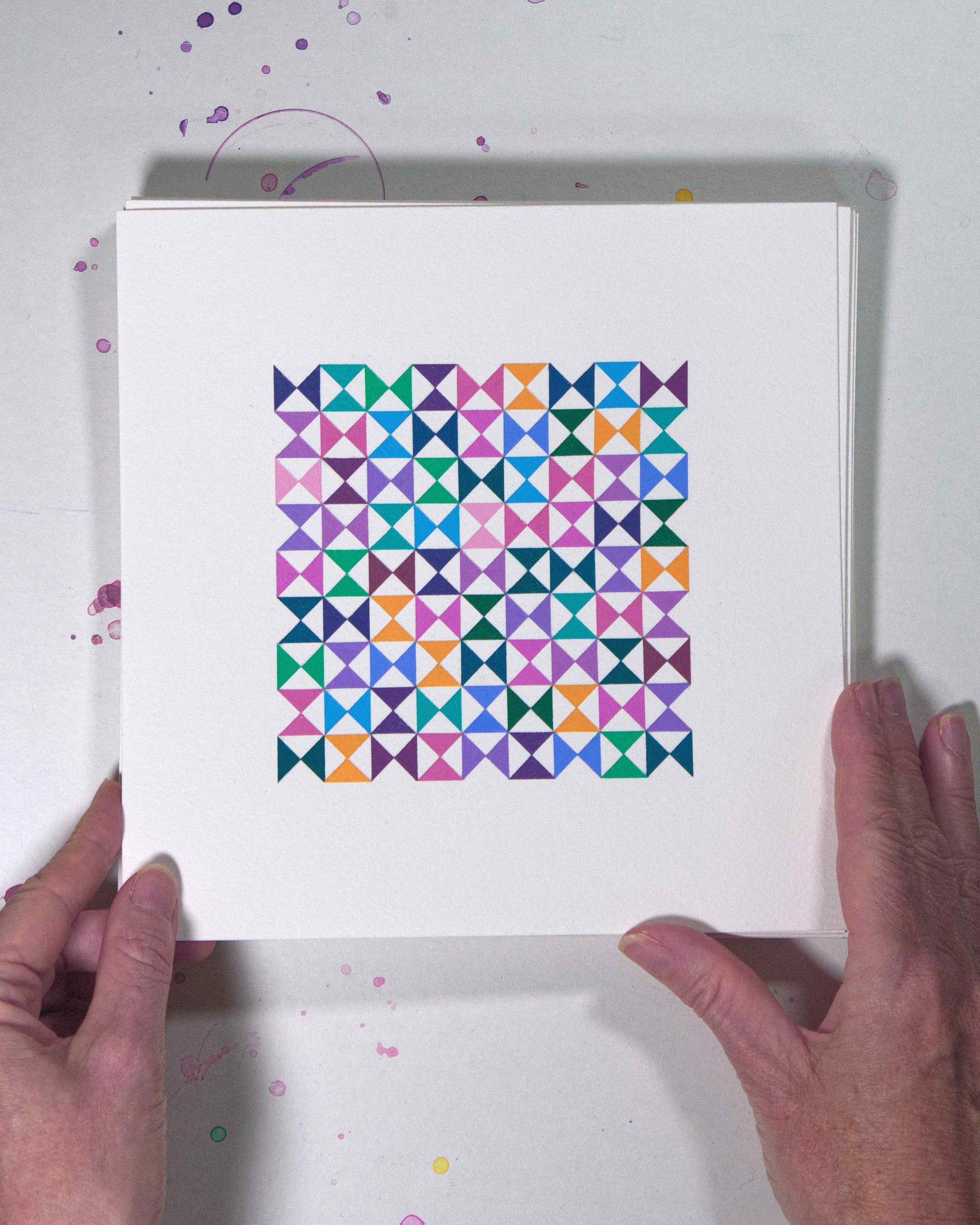 Hands holding a bold, graphic multicoloured abstract painting with repeating geometric shapes, 8 July – 008/365 (46211/365) by Victoria Mardon, 365: A Year in Colour series.