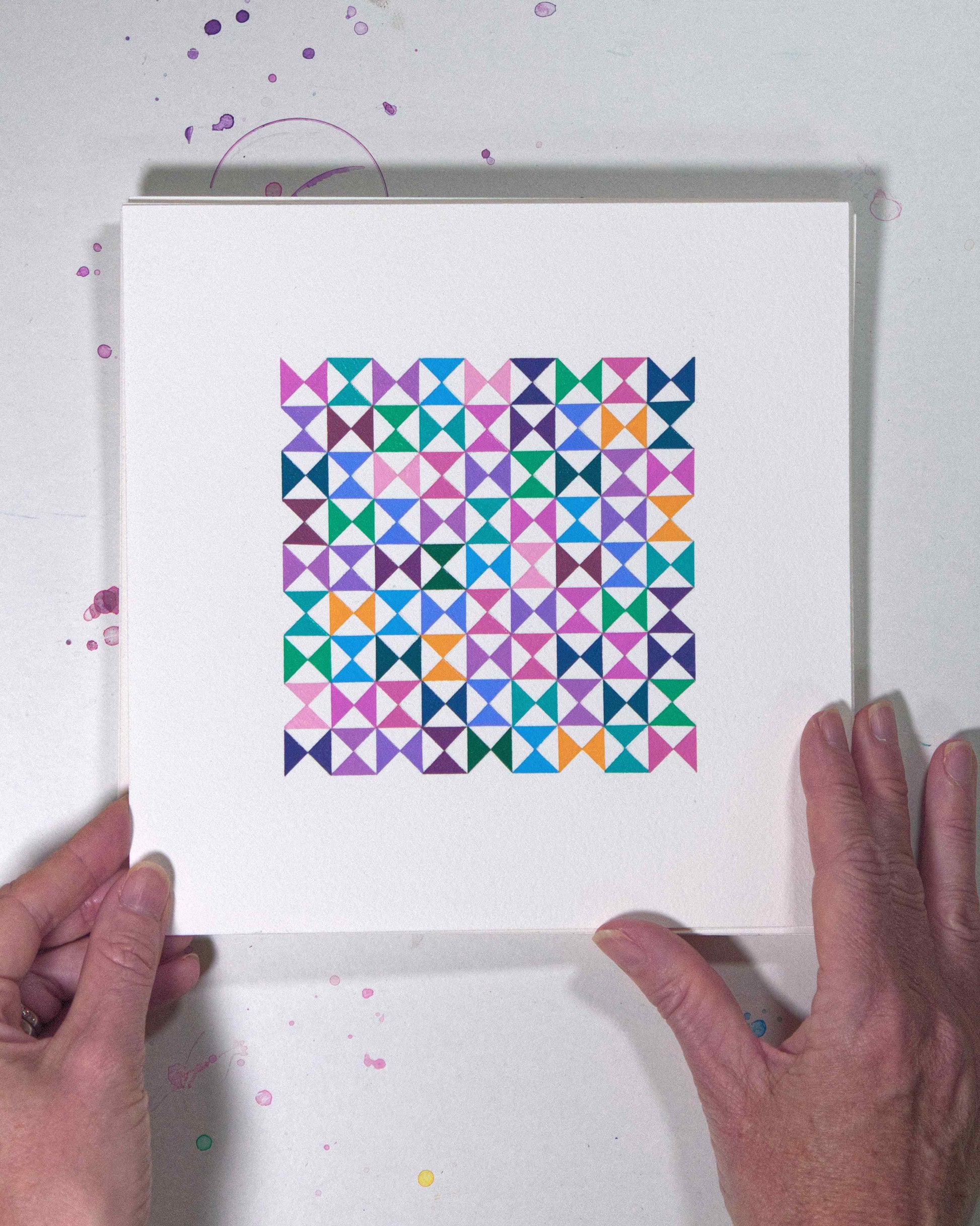 Hands holding a bold, graphic multicoloured abstract painting with repeating geometric shapes, 16 July – 016/365 (46219/365) by Victoria Mardon, 365: A Year in Colour series.