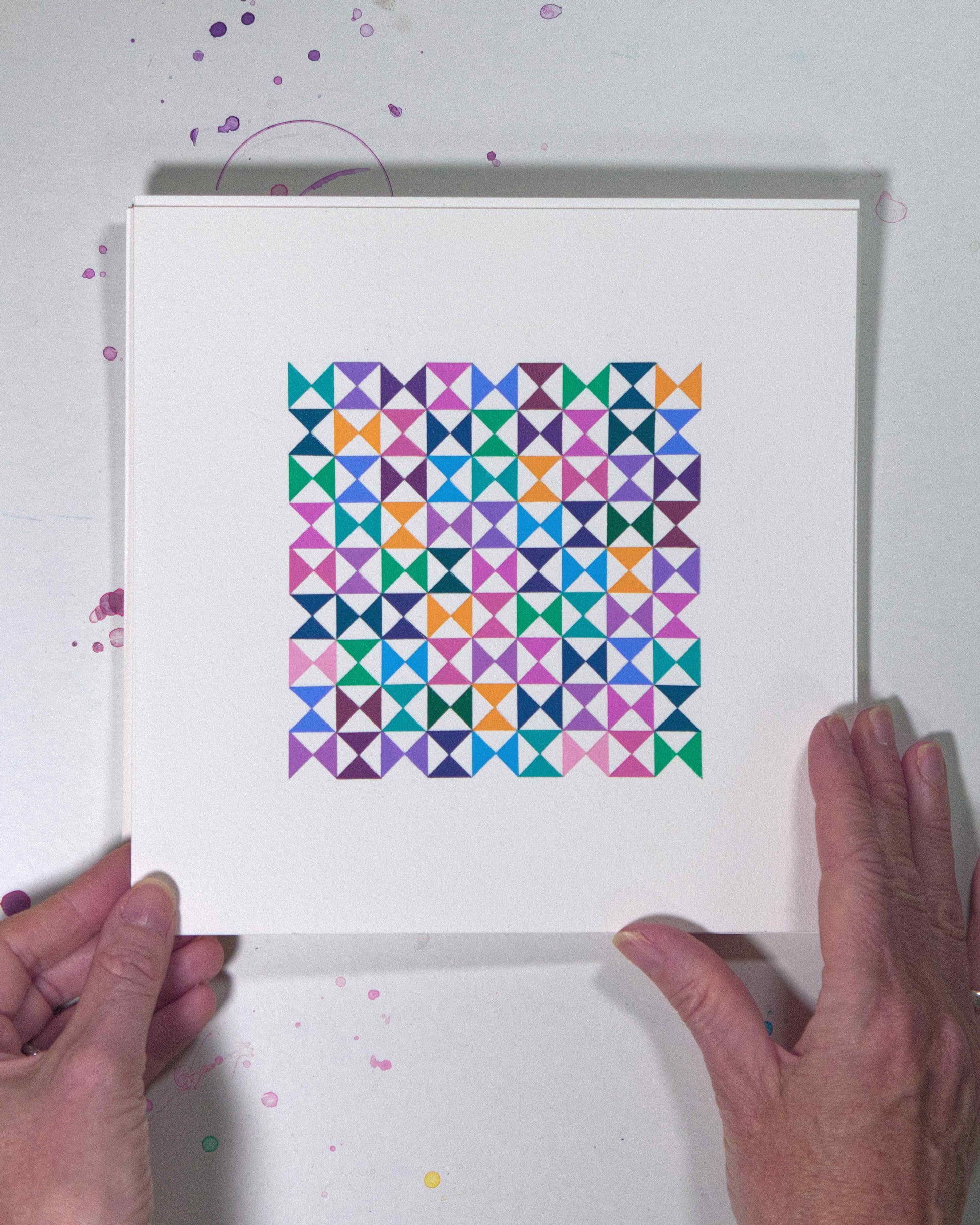 Hands holding a bold, graphic multicoloured abstract painting with repeating geometric shapes, 19 July – 019/365 (46222/365) by Victoria Mardon, 365: A Year in Colour series.