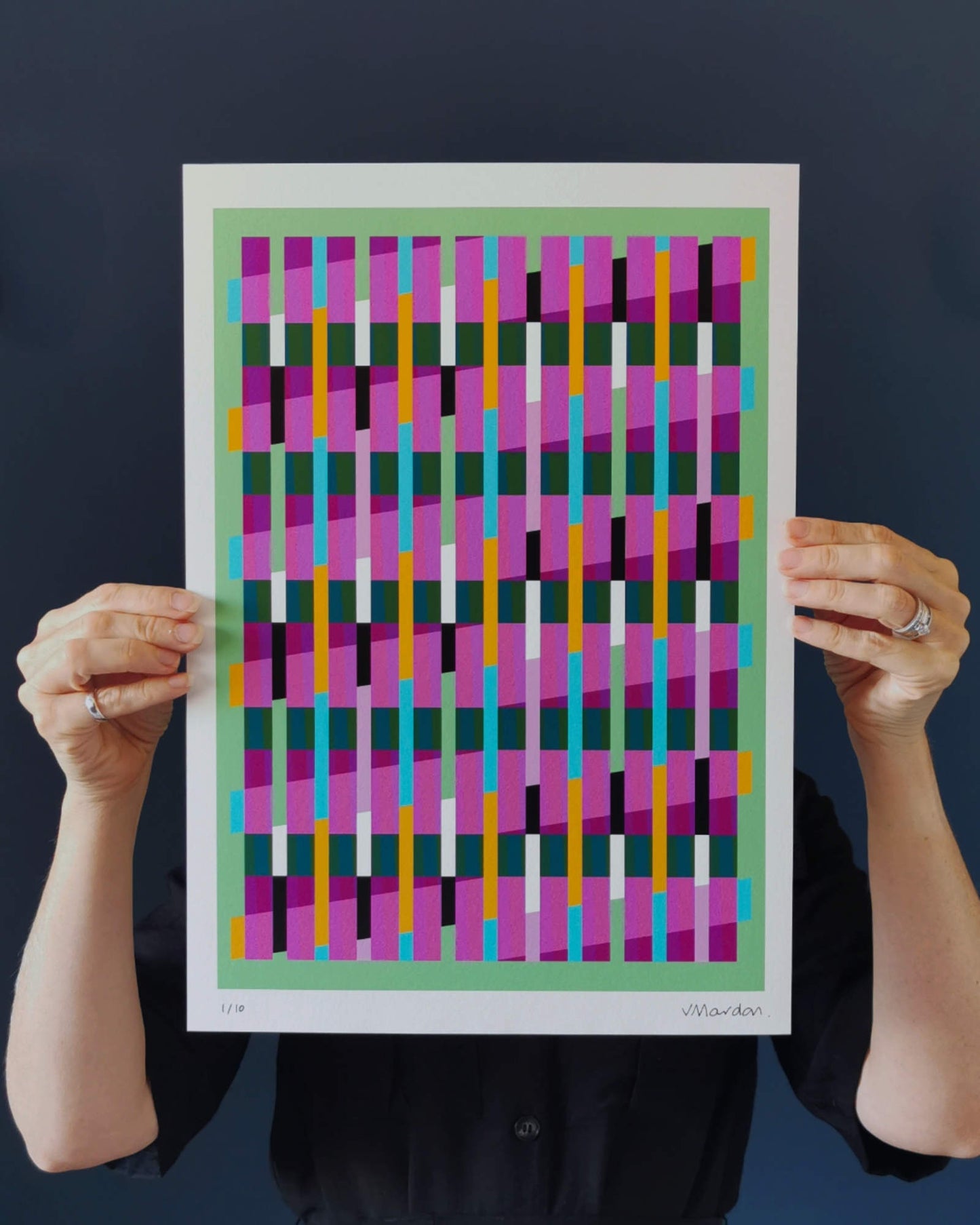 Green geometric abstract giclée print by Victoria Mardon held in hands against a dark background